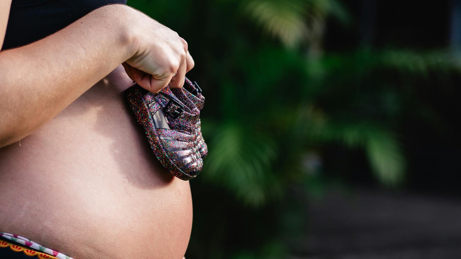 Pregnant woman holding a shoe in her hand