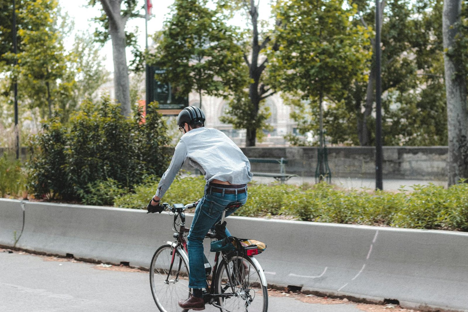 Faceless man riding bicycle along sunny street